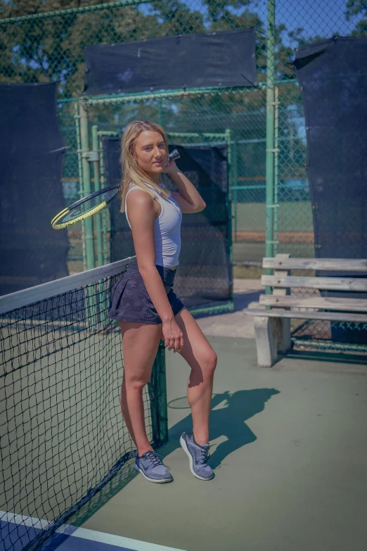 a beautiful young blonde holding a tennis racquet standing on a tennis court