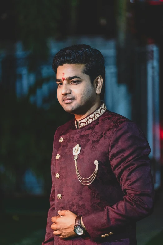 an indian man wearing a purple outfit and jewelled collar