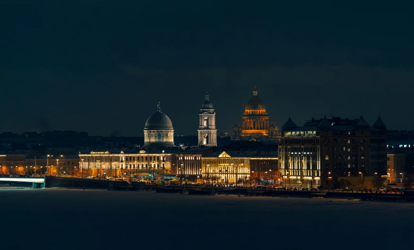 an illuminated city sits below a cloudy night sky