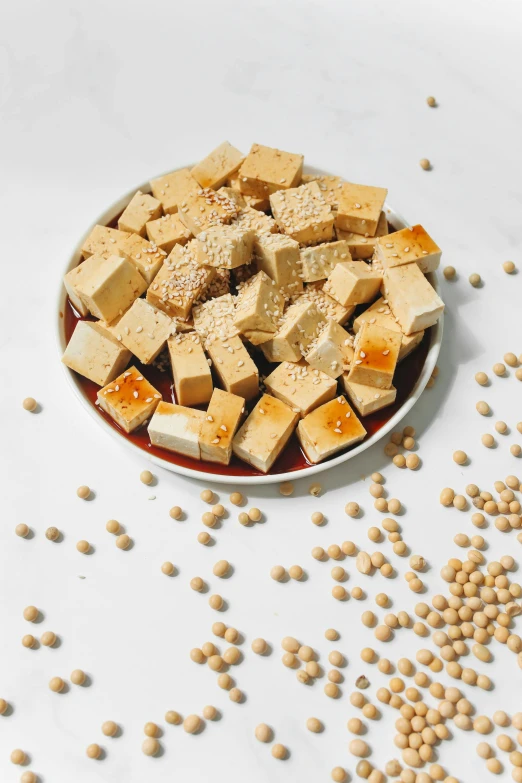 a bowl of tofu and some soy seeds scattered around