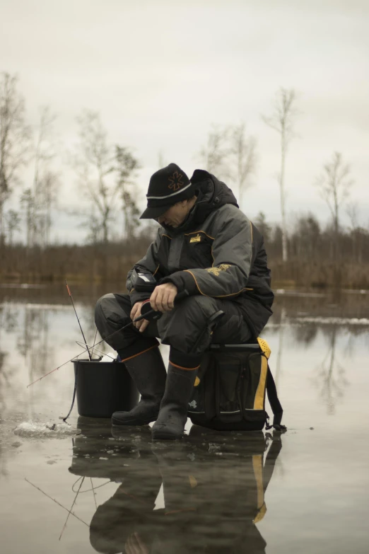 a man in black jacket and hat kneeling on a flooded area