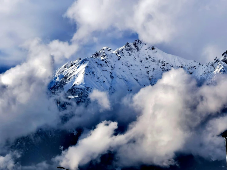 a snowy mountain is standing above the clouds