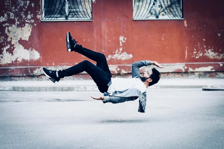 a man doing tricks in the street while holding his legs up