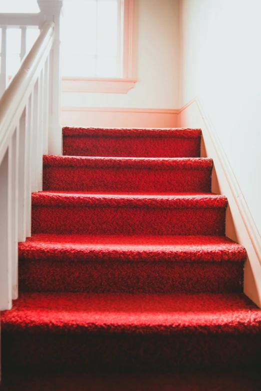 a stair case with red carpet, and white railing