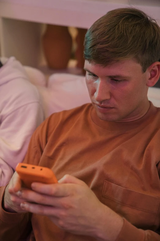 a young man with an orange remote sitting down