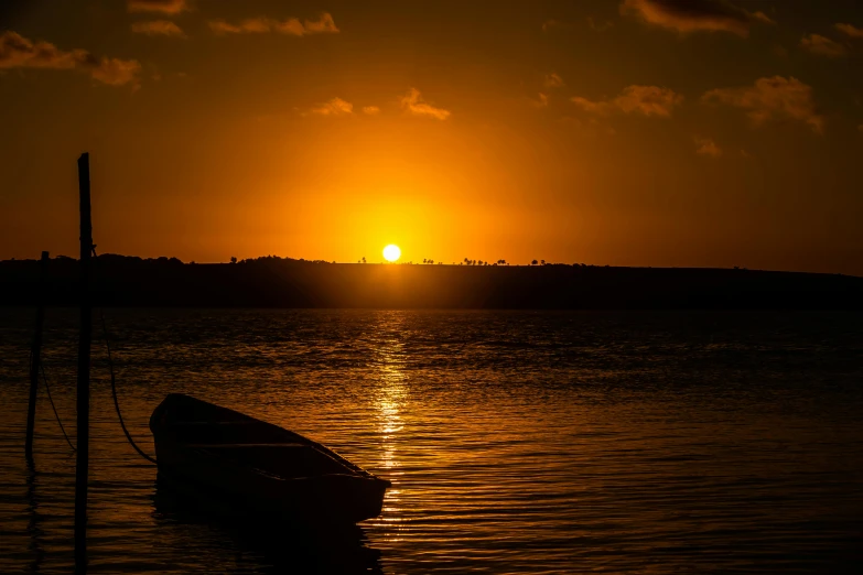 a boat in the water at sunset with a view of the sun setting