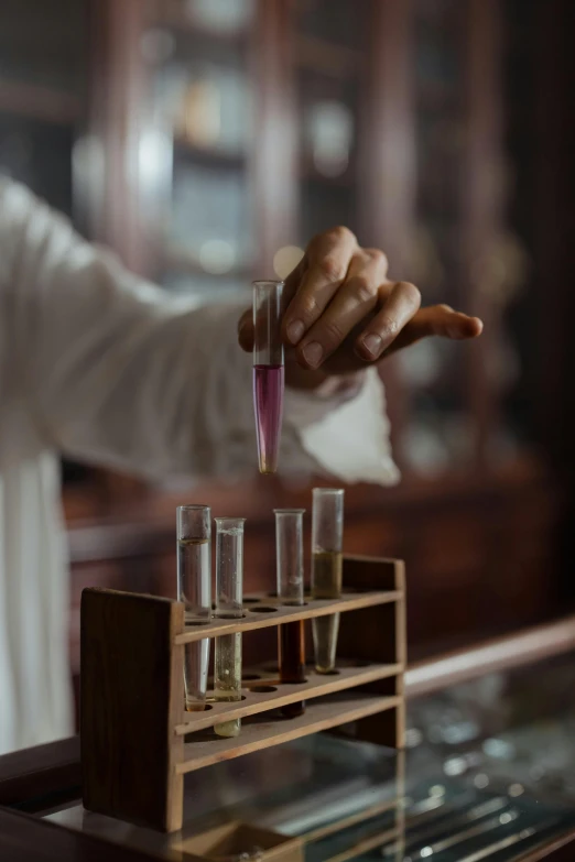 a person is making drinks with the help of some hand holding test tubes