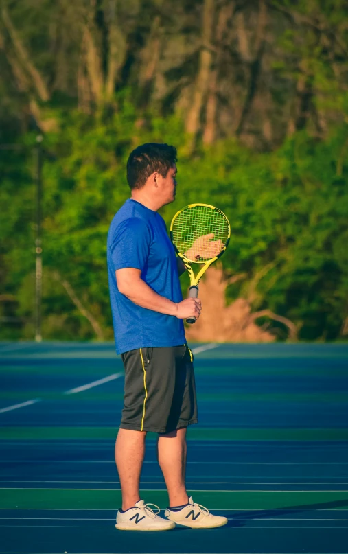 a person in a blue shirt and gray shorts holding a racket