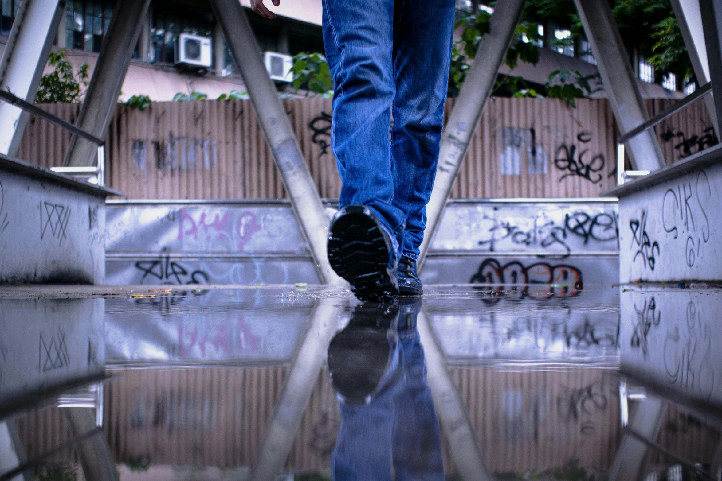 a man standing on top of a glass floor in front of graffiti covered walls