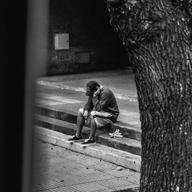 a man sits on the curb and looks into a mirror
