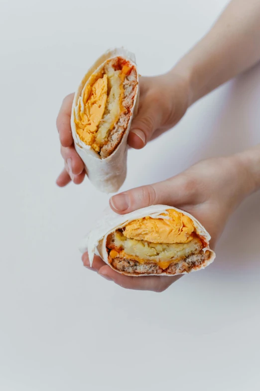 two hands holding together a burrito sandwich