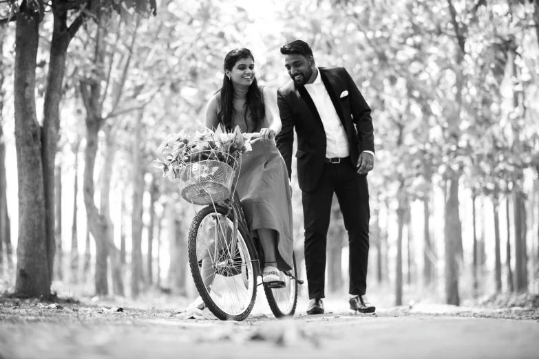 black and white image of bride riding a bike in a forest
