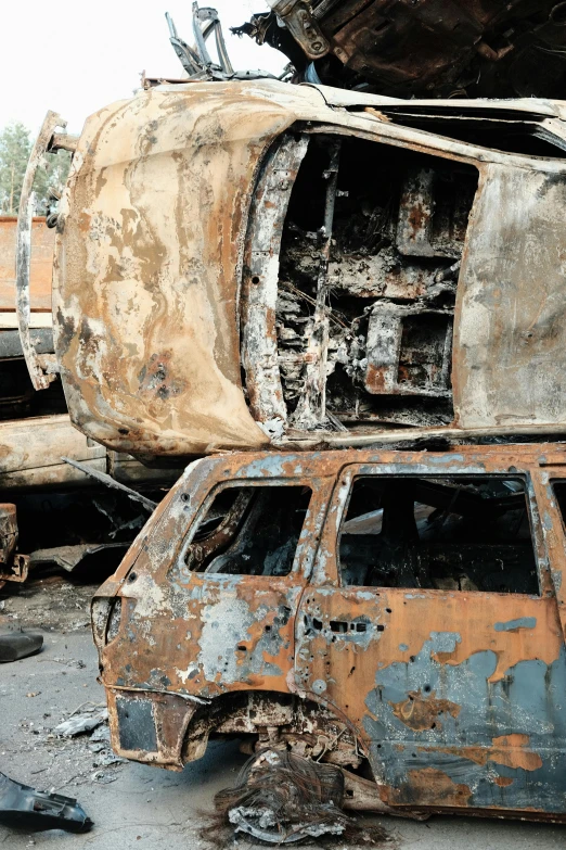 two old cars in a junkyard with one car burned out