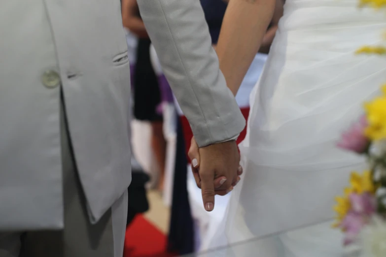 a close up s of a bride and groom holding hands