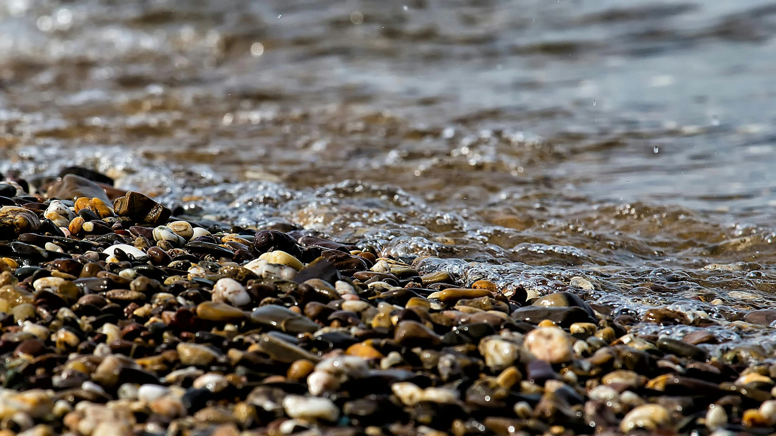 many pebbles and other types of rocks on the beach