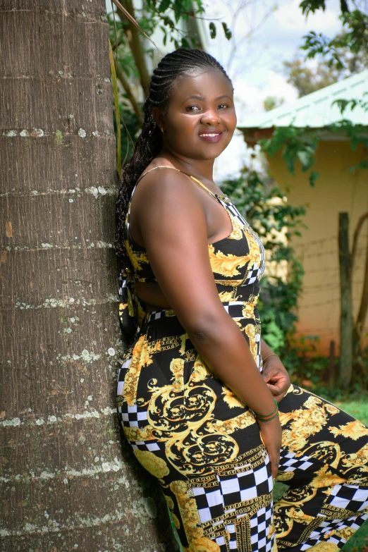 woman leaning up against tree in bright patterned dress