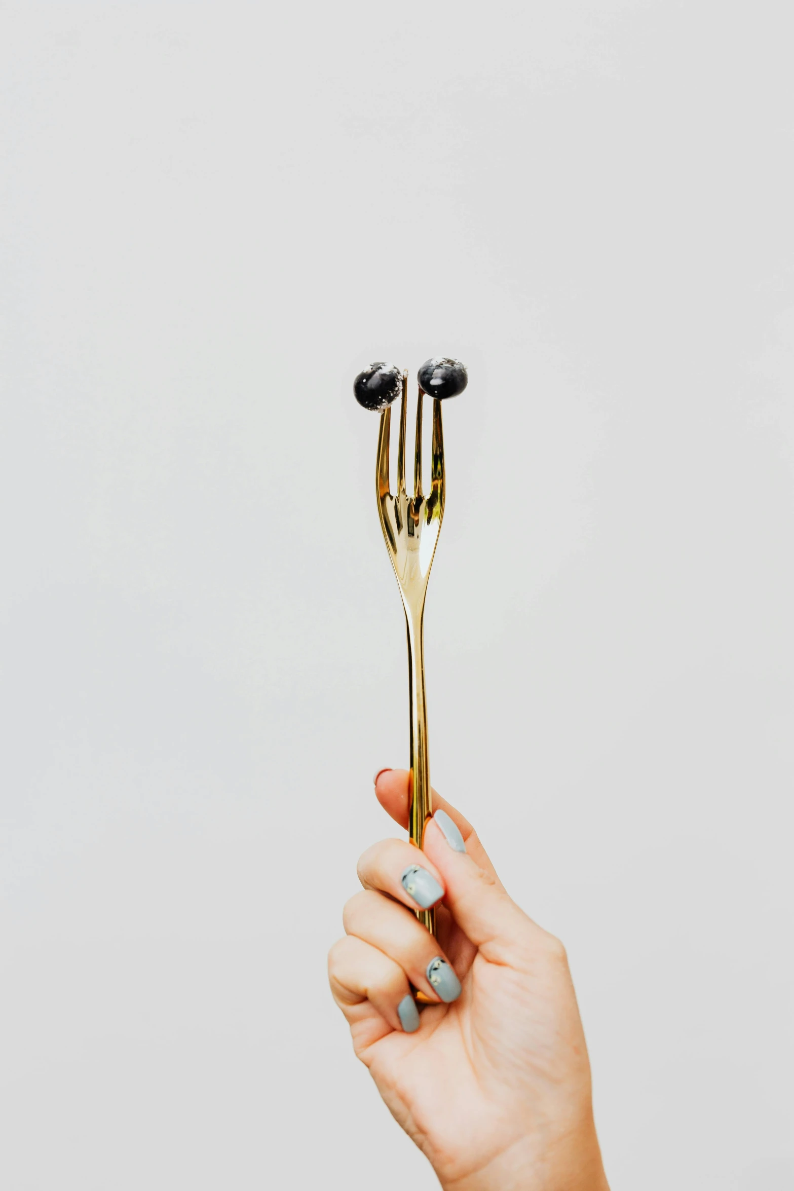 the woman holds a large gold fork with two forks on it