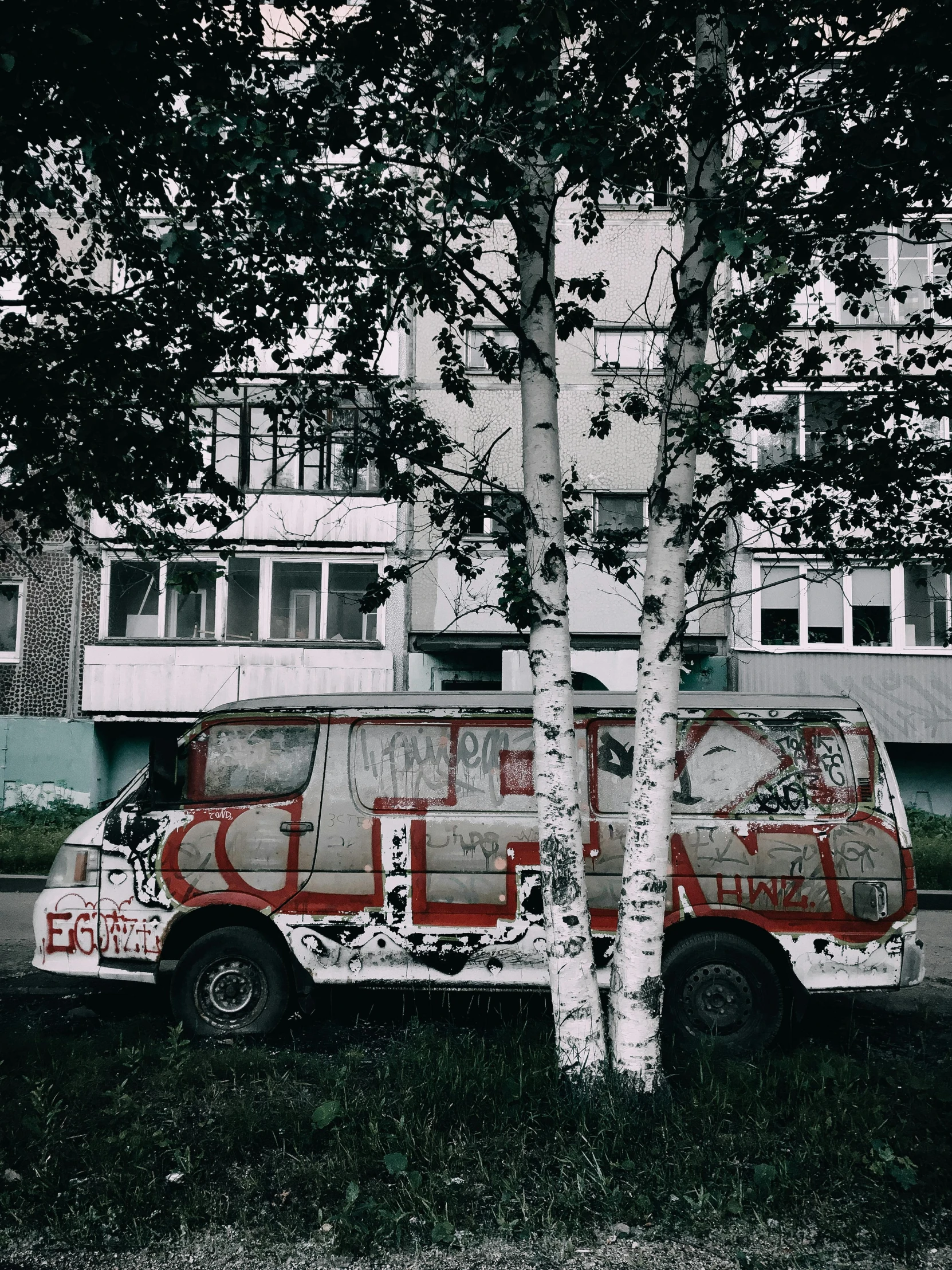 a van painted red next to a tree and a building