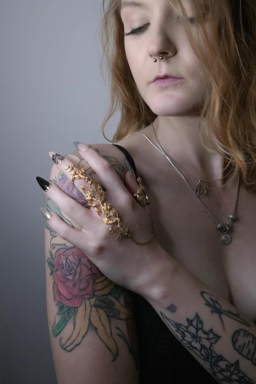 a woman wearing tattoos holds her hands together