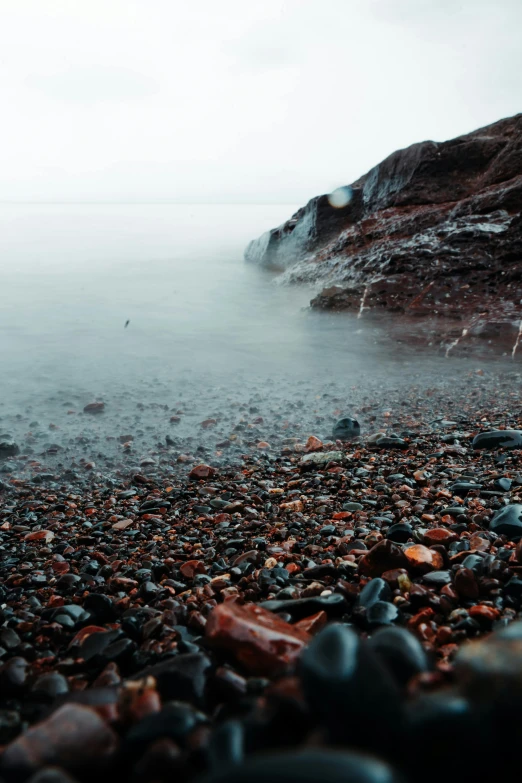 rocks on the sand and water with a body of water