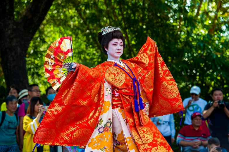 a woman dressed in traditional chinese clothing and holding a red fan