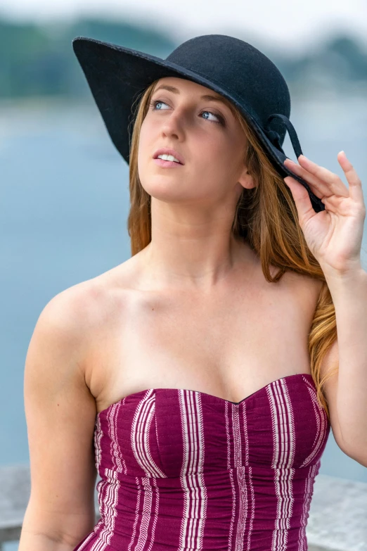 the woman is wearing a hat outside and looking at the water