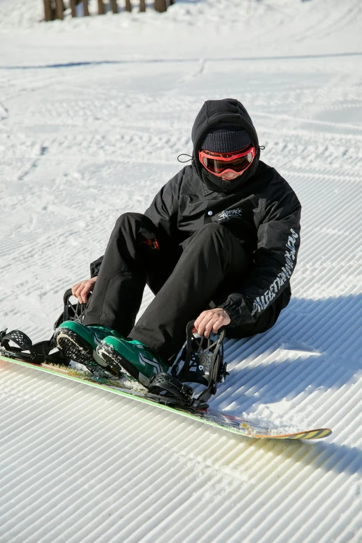 a man is sitting in the snow while he holds his skis on his knees