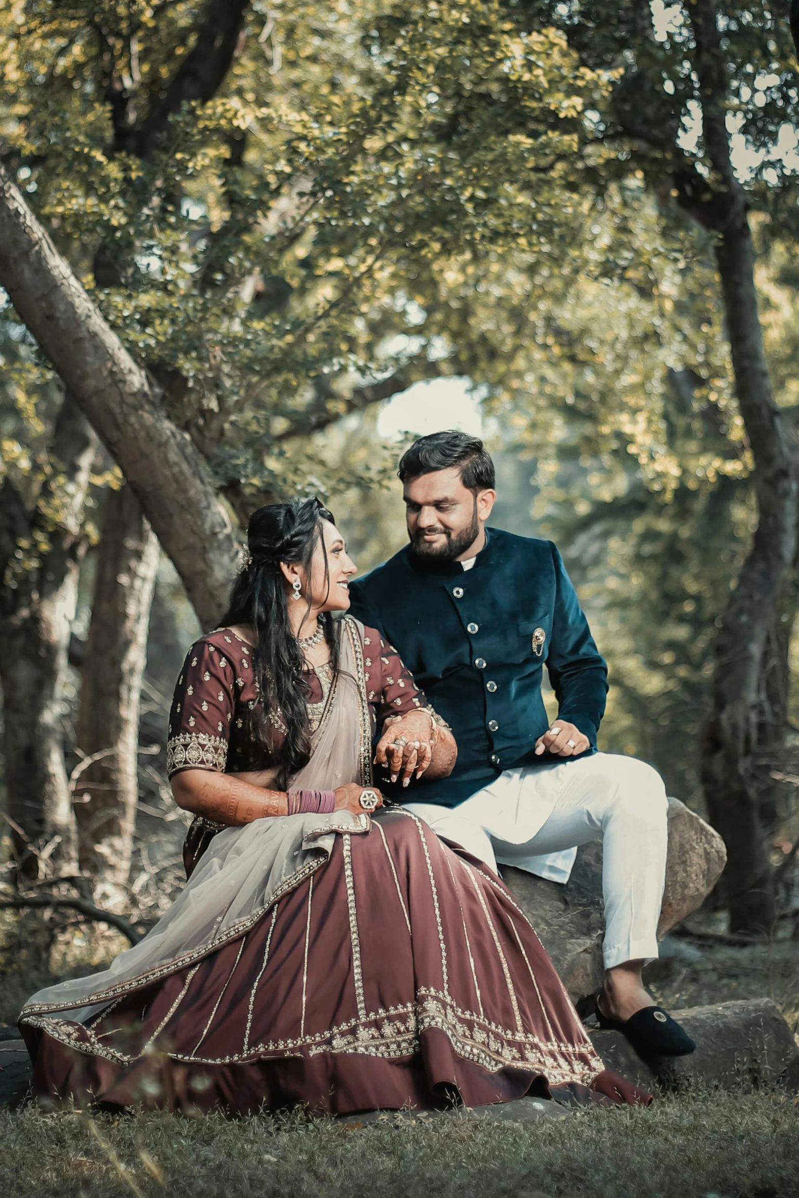 man and woman dressed in indian style clothing sitting on rock