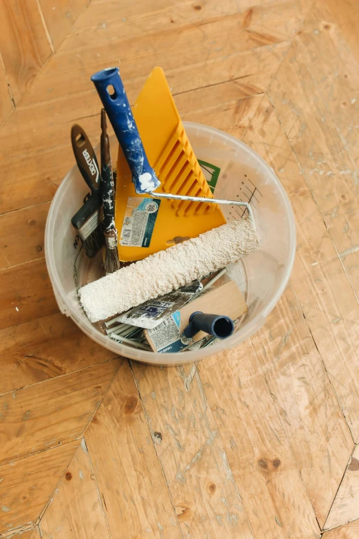 a plastic container containing assorted materials on a wooden floor