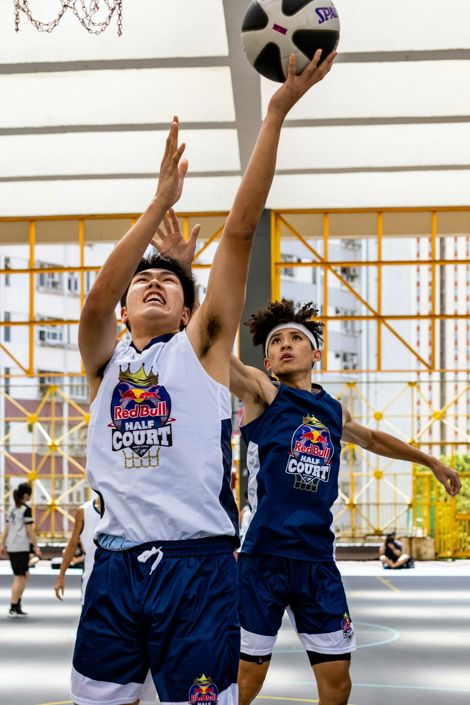 two young men playing basketball in an indoor court