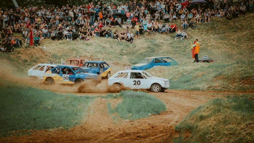 two cars driving through the mud while people watch