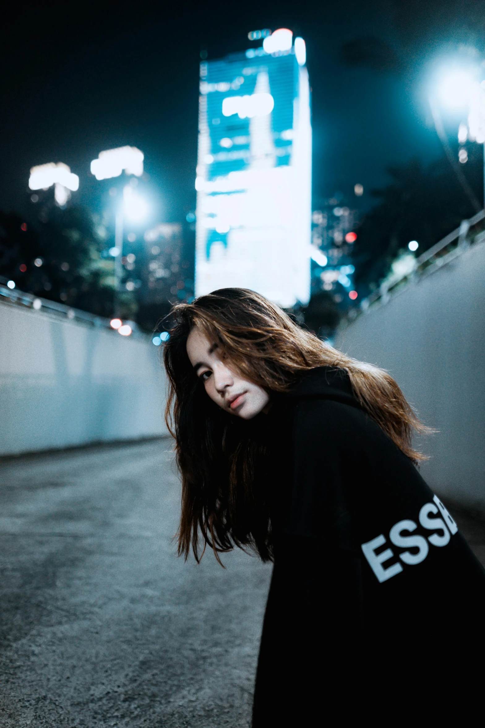 a woman with long hair leans on a wall