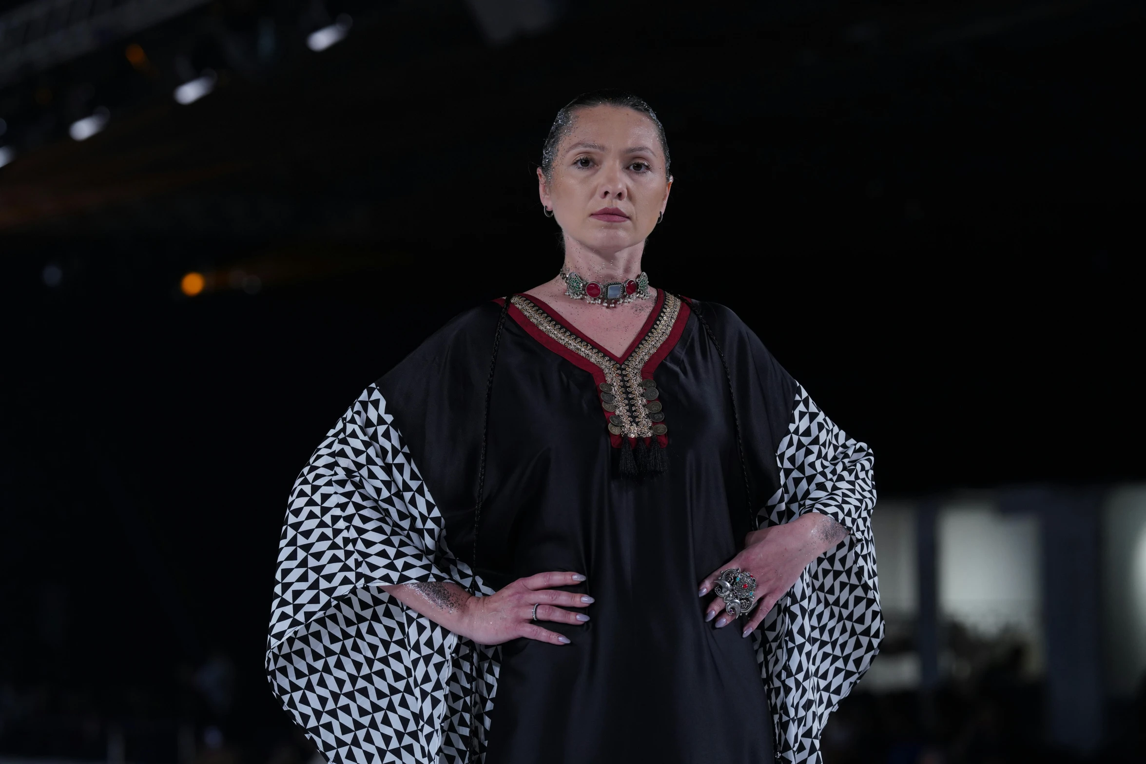 a woman in black and white dress standing on a runway