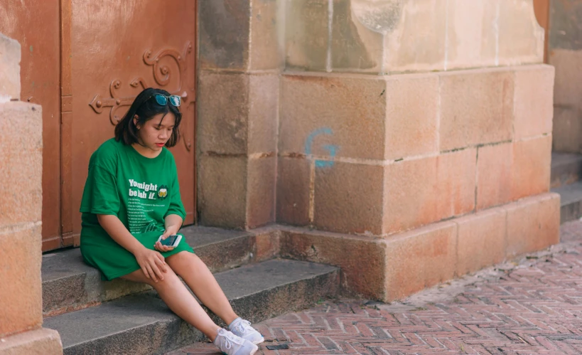 a little girl sitting on the side of steps next to her cell phone