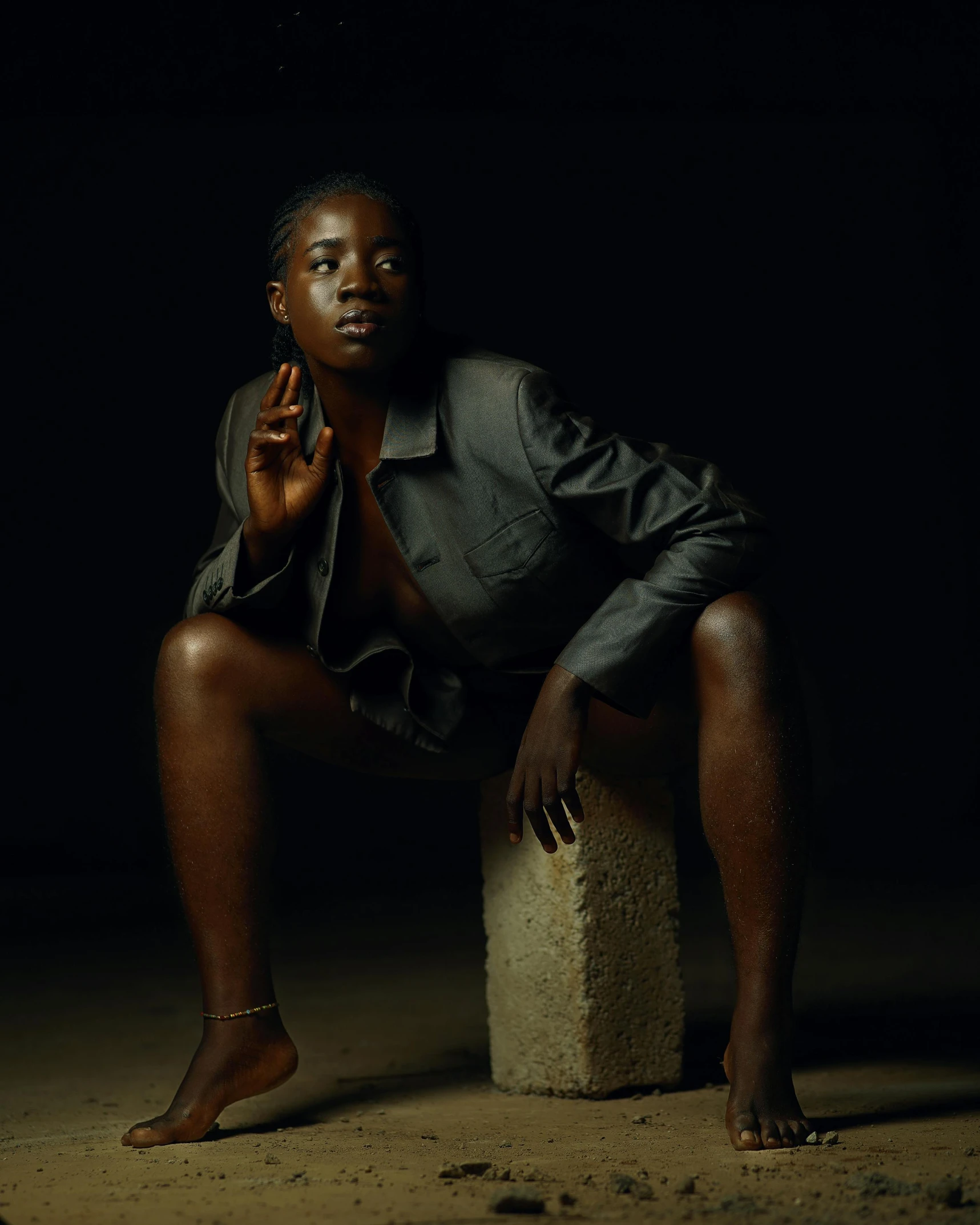an african woman sitting on a rock wearing a jacket