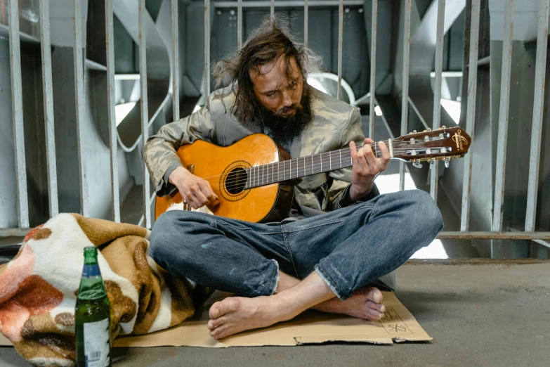 a man sitting on a blanket holding an ukulele