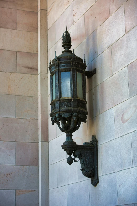 an iron and glass lamp is on the corner of a building