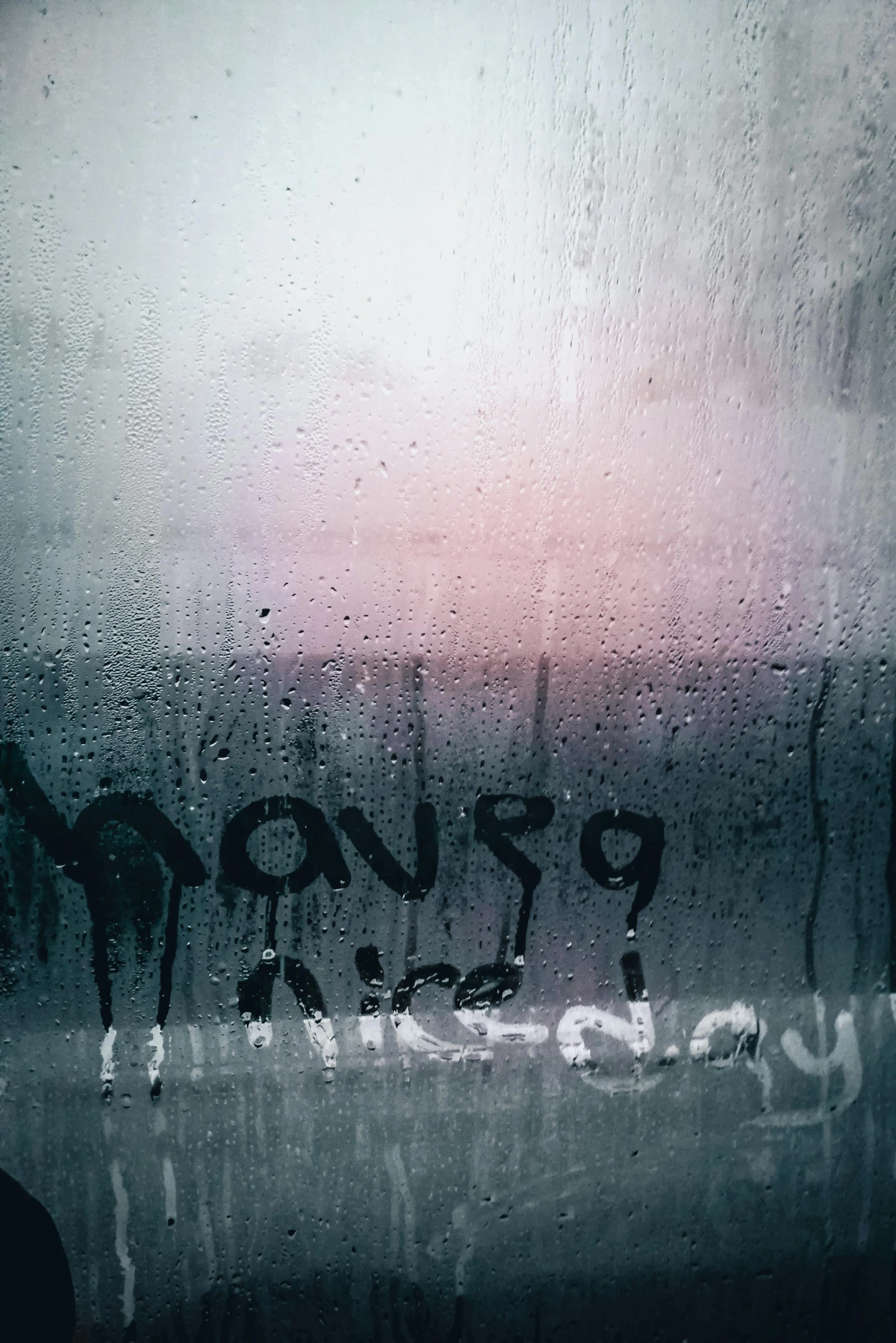 rain drops down and onto a window with graffiti
