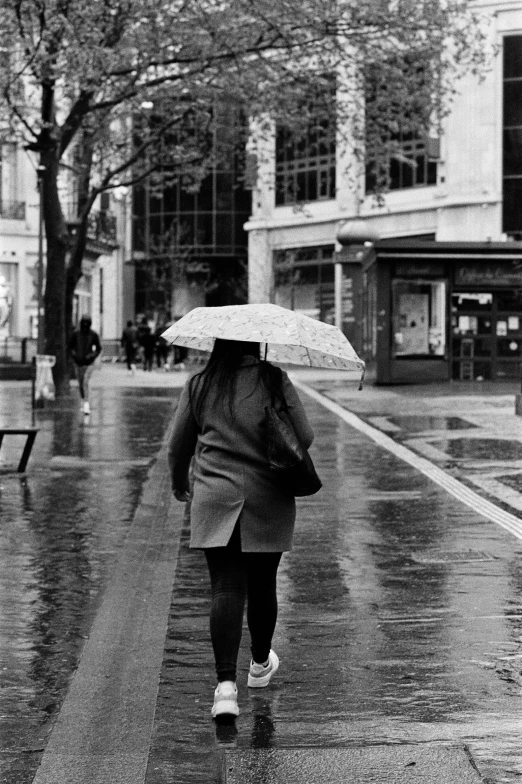 a person walking in the rain holding an umbrella