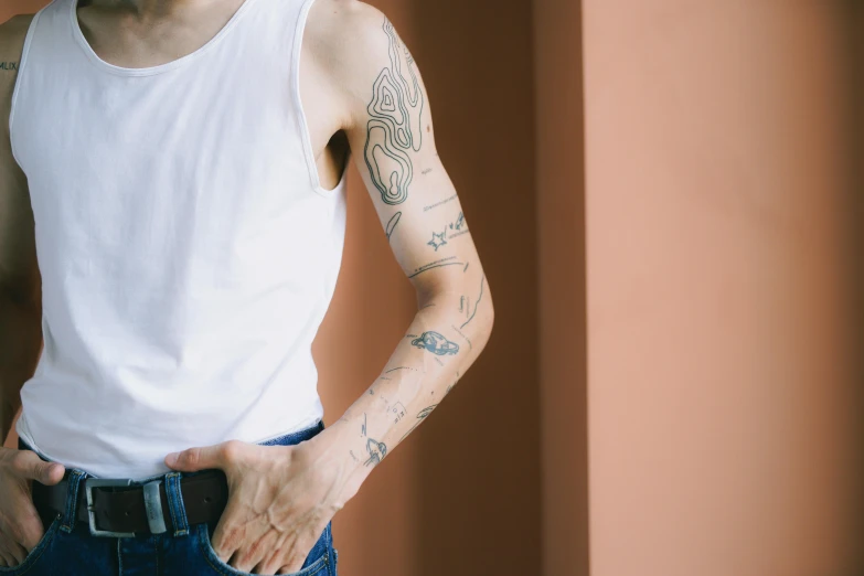 a man with tattoos on his arm wearing jeans