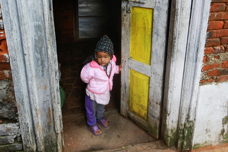 a little girl holding a bat out to an open door