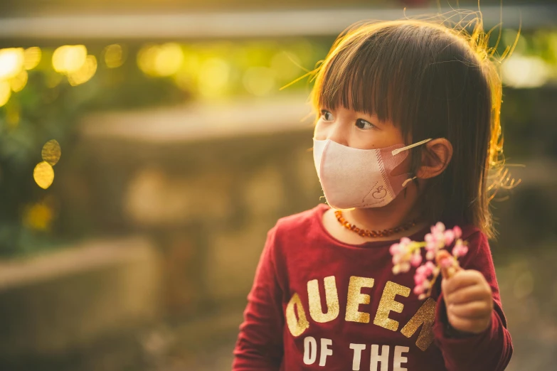 a girl with a face mask holding flowers