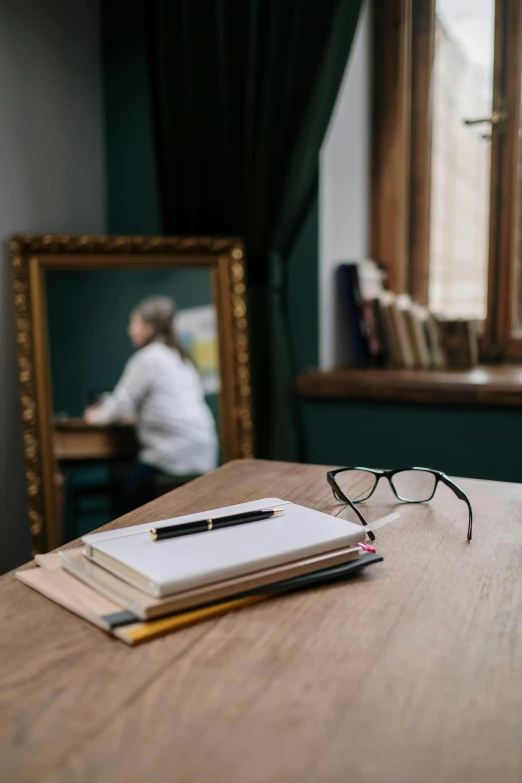 a mirror, notebook and pen are sitting on the counter top