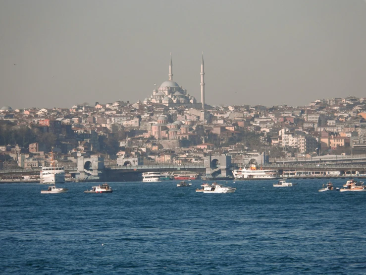 several fishing boats on water with large city in background