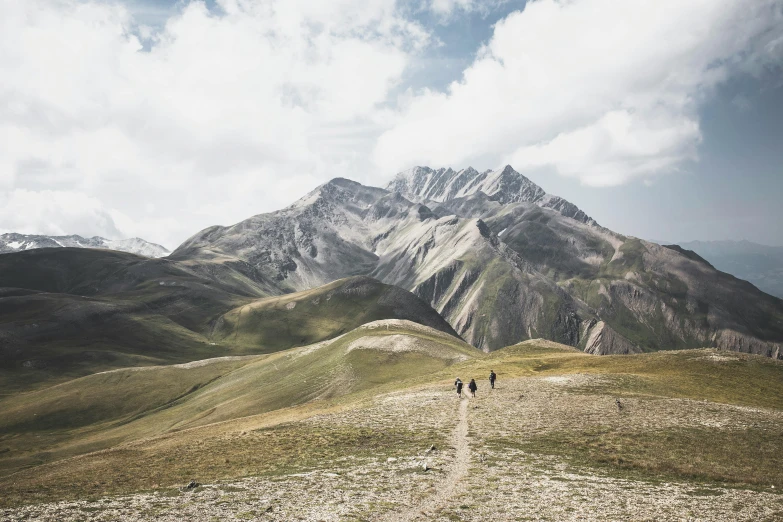 three people hiking on a mountain top in the distance