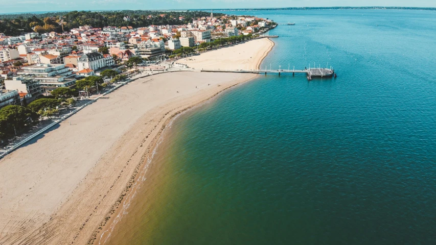 a beach in front of a town with a pier