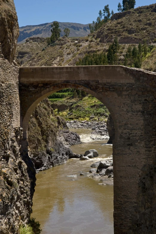 a bridge is made out of stone and a creek flows under it