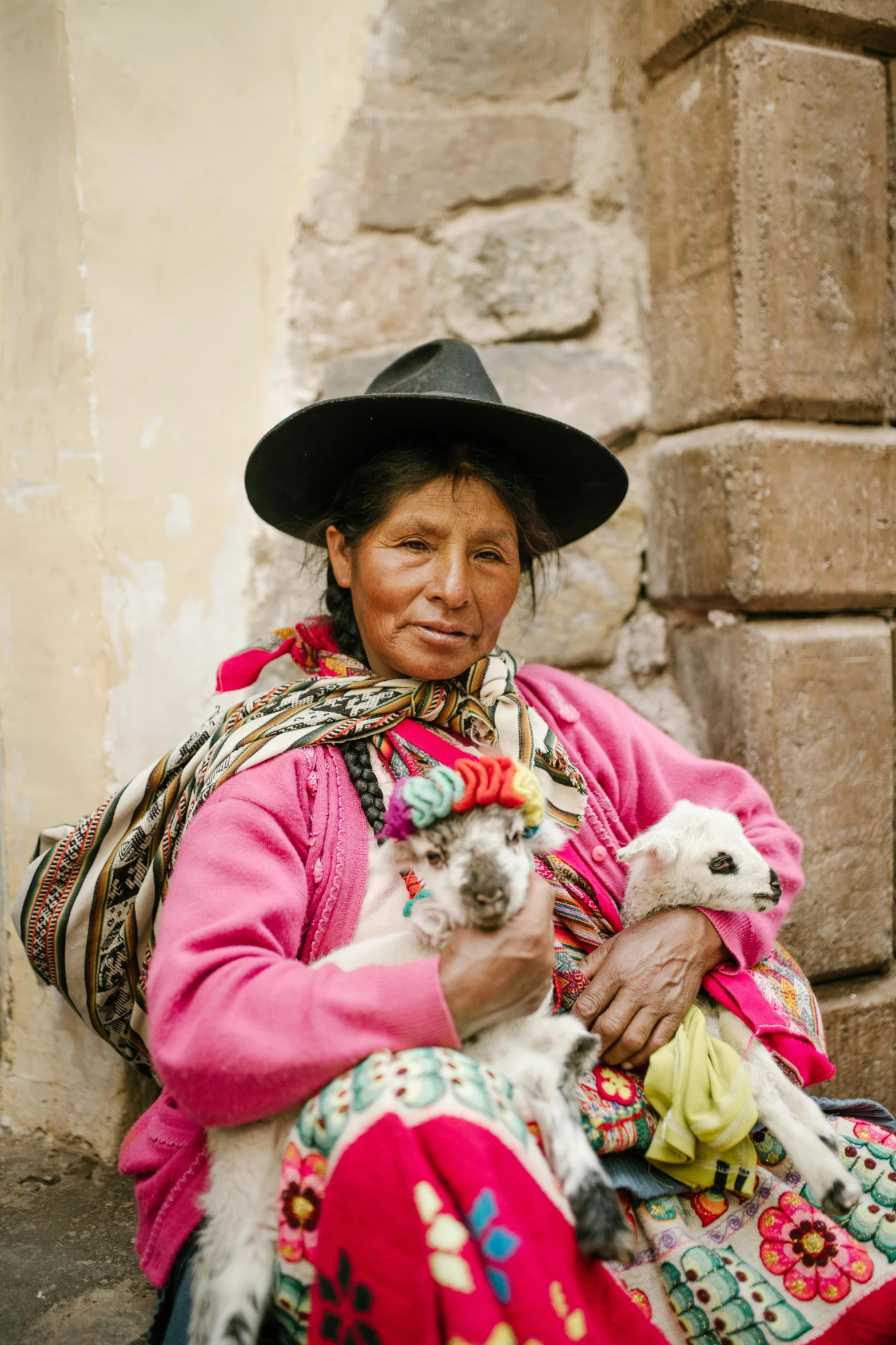 an older woman wearing a colorful outfit and holding a small dog