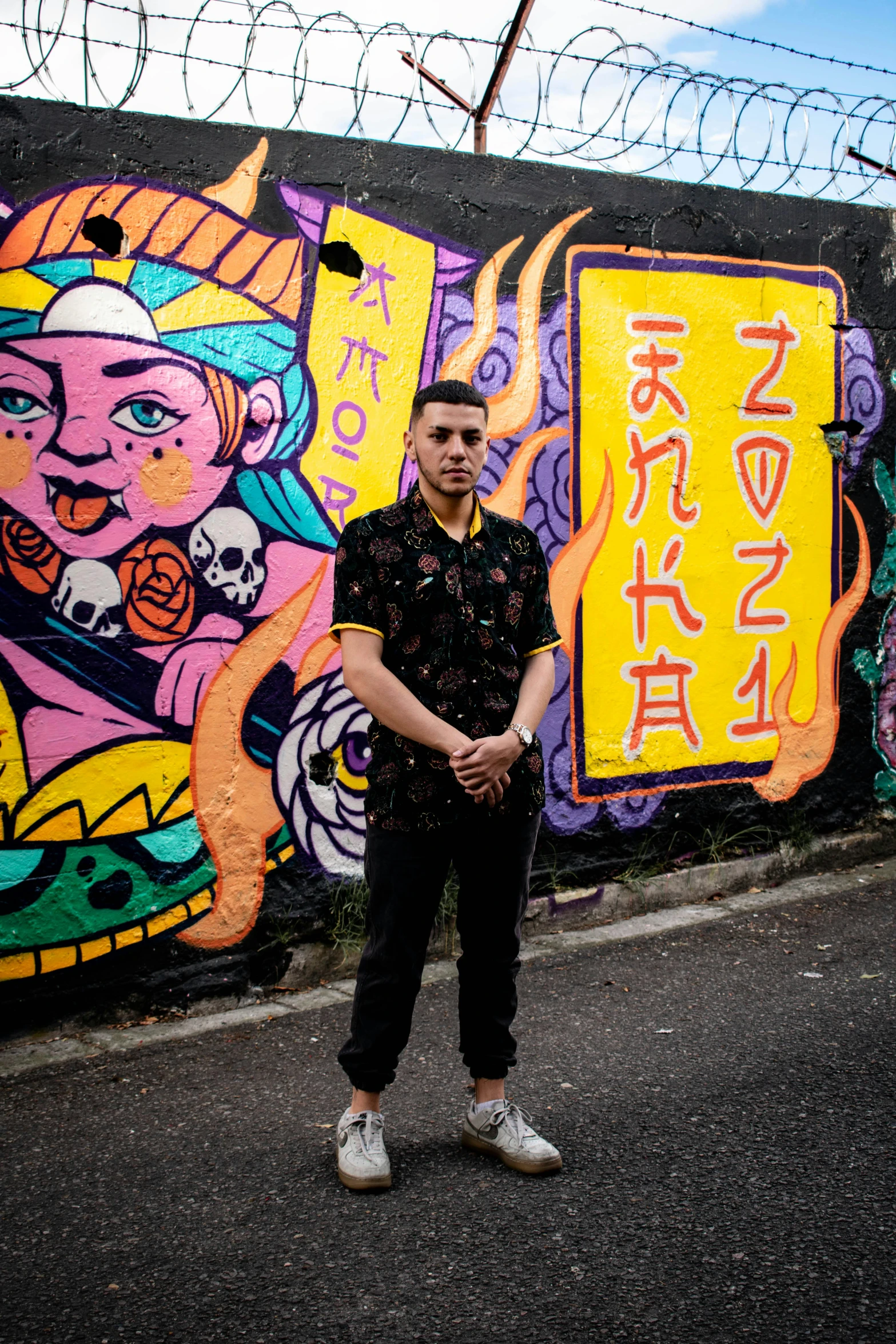 a man stands in front of a graffiti wall