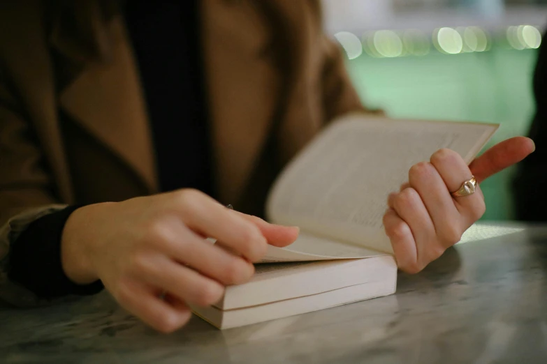 a woman's hands and ring as she opens a book